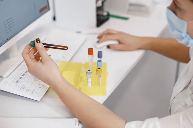 Une employée de laboratoire étiquette des échantillons de sang à son bureau